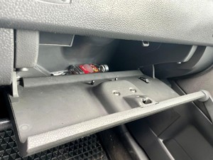 Zdjęcie przedstawia: otwarty schowek samochodowy i leżącą w nim butelkę z alkoholem.