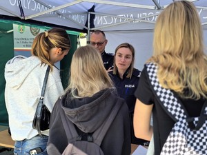Zdjęcie przedstawia: policjantkę i policjanta rozmawiających z młodymi dziewczynami.