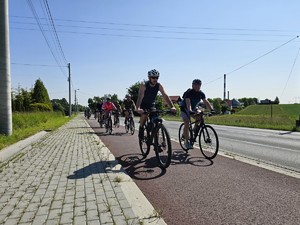 Zdjęcie przedstawia: ludzi jadących na rowerach.