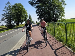 Zdjęcie przedstawia: dwie kobiety jadące na rowerach.