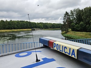 Zdjęcie przedstawia: radiowóz i zbiornik wodny.