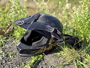 Zdjęcie przedstawia: kask motocyklowy leżący na trawie.
