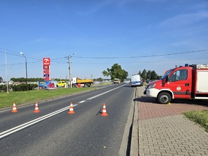 Zdjęcie przedstawia: słupki ostrzegawcze leżące na drodze oraz wóz straży pożarnej.