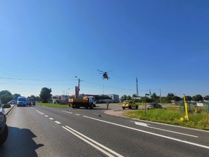 Zdjęcie przedstawia: śmigłowiec pogotowia, lądujący na drodze.