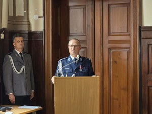 Zdjęcie przedstawia: umundurowanego policjanta, stojącego przy mównicy.