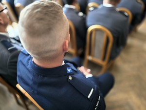 Zdjęcie przedstawia: element munduru na ramieniu policjanta.