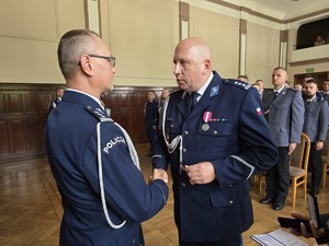 Zdjęcie przedstawia: dwóch umundurowanych policjantów podających sobie rękę.