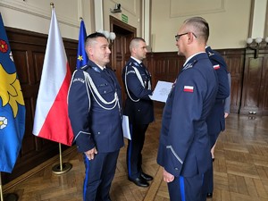 Zdjęcie przedstawia: czterech policjantów stojących na przeciwko siebie.