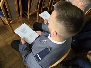 Zdjęcie przedstawia: umundurowana osobę trzymająca teczkę w ręce.