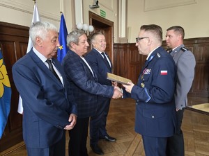 Zdjęcie przedstawia: policjanta podającego rękę mężczyźnie.