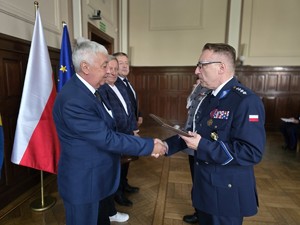 Zdjęcie przedstawia: policjanta ściskającego dłoń mężczyzny.