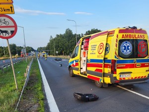 Zdjęcie przedstawia: samochód pogotowia ratunkowego i przewrócony motor.
