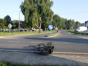 Zdjęcie przedstawia: przewrócony rower leżący na drodze.