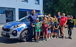 Zdjęcie przedstawia: policjantów z dziećmi przy policyjnym radiowozie.