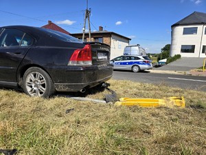Zdjęcie przedstawia: pojazd, który uderzył w znak drogowy i radiowóz.