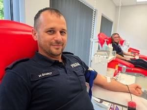 Zdjęcie przedstawia: dwóch umundurowanych policjantów, siedzących obok siebie, którzy oddają krew.