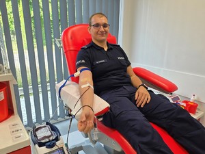 Zdjęcie przedstawia: policjanta siedzącego na fotelu, który oddaje krew.