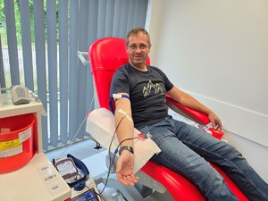 Zdjęcie przedstawia: mężczyznę na fotelu, w trakcie pobierania krwi.