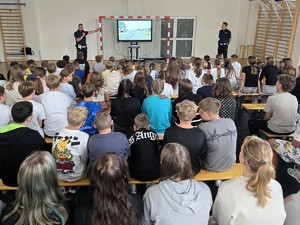 Zdjęcie przedstawia: policjanta pokazującego dziedzicom zdjęcie drogi.