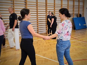 Zdjęcie przedstawia: dwie kobiety trzymające się za ręce.