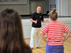 Zdjęcie przedstawia: Osobę prowadząca trening, która wydaje polecenia grupie.