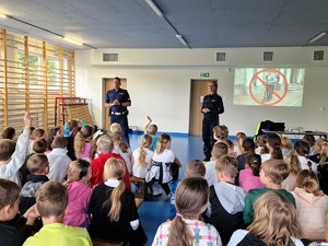 Zdjęcie przedstawia: dwóch umundurowanych policjantów prowadzących pogadankę.