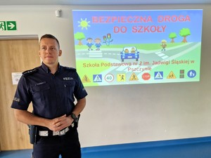 Zdjęcie przedstawia: umundurowanego policjanta prowadzącego pogadankę.