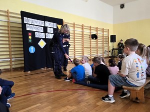 Zdjęcie przedstawia: policjantkę, która podaje dziecku mikrofon.
