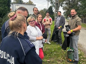 Zdjęcie przedstawia: Dwóch umundurowanych policjantów wraz z uczestnikami wspólnego sprzątania świata.
