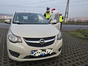 Zdjęcie przedstawia umundurowanego policjanta oraz samochód osobowy.