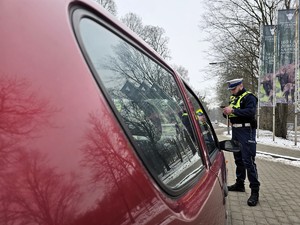 Zdjęcie przedstawia umundurowanego policjanta oraz samochód osobowy.