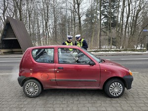 Zdjęcie przedstawia dwóch umundurowanych policjantów oraz samochód osobowy.
