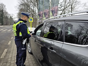Zdjęcie przedstawia umundurowanego policjanta oraz samochód osobowy.