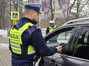 Zdjęcie przedstawia dwóch umundurowanych policjantów oraz samochód osobowy.