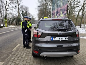 Zdjęcie przedstawia dwóch umundurowanych policjantów oraz samochód osobowy.