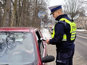 Zdjęcie przedstawia umundurowanego policjanta oraz samochód osobowy.