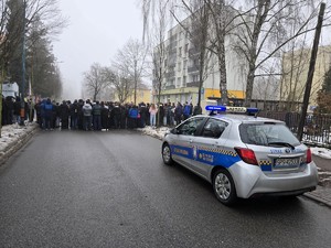 Zdjęcie przedstawia uczestników uroczystości oraz radiowóz straży miejskiej.