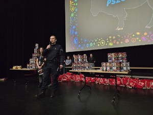 Zdjęcie przedstawia umundurowanego policjanta oraz uczestników wydarzenia.