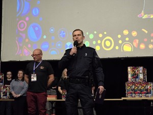 Zdjęcie przedstawia uczestników wydarzenia oraz umundurowanego policjanta.