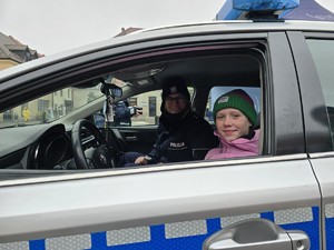Zdjęcie przedstawia uczestników wydarzenia oraz umundurowaną policjantkę.