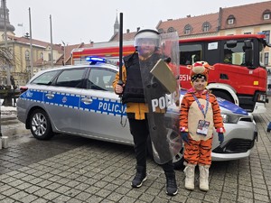 Zdjęcie przedstawia uczestników wydarzenia oraz oznakowany radiowóz.