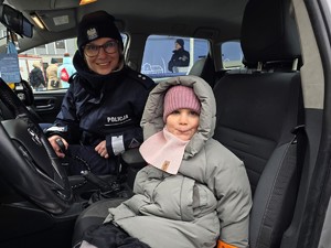 Zdjęcie przedstawia umundurowaną policjantkę oraz uczestników wydarzenia.