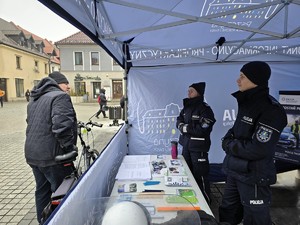 Zdjęcie przedstawia dwóch umundurowanych policjantów oraz uczestników wydarzenia.