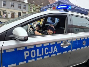 Zdjęcie przedstawia uczestników wydarzenia w radiowozie.
