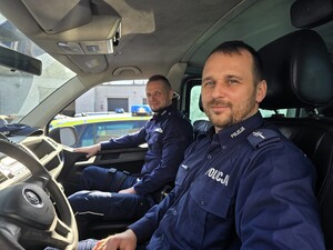 Zdjęcie przedstawia dwóch umundurowanych policjantów w radiowozie.