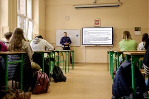 Na zdjęciu znajdują się uczniowie biorący udział w spotkaniu oraz umundurowany policjant.