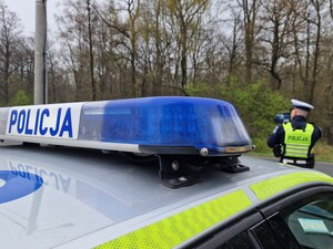 Na zdjęciu znajduje się radiowóz oraz umundurowany policjant.