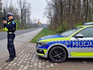 Na zdjęciu znajduje się radiowóz oraz umundurowany policjant.