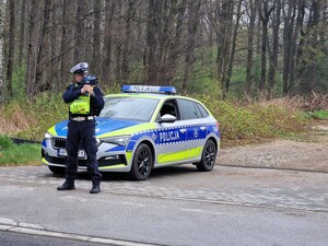 Na zdjęciu znajduje się radiowóz oraz umundurowany policjant.