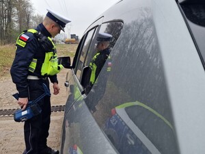 Na zdjęciu znajduje się umundurowany policjant obok samochodu osobowego.